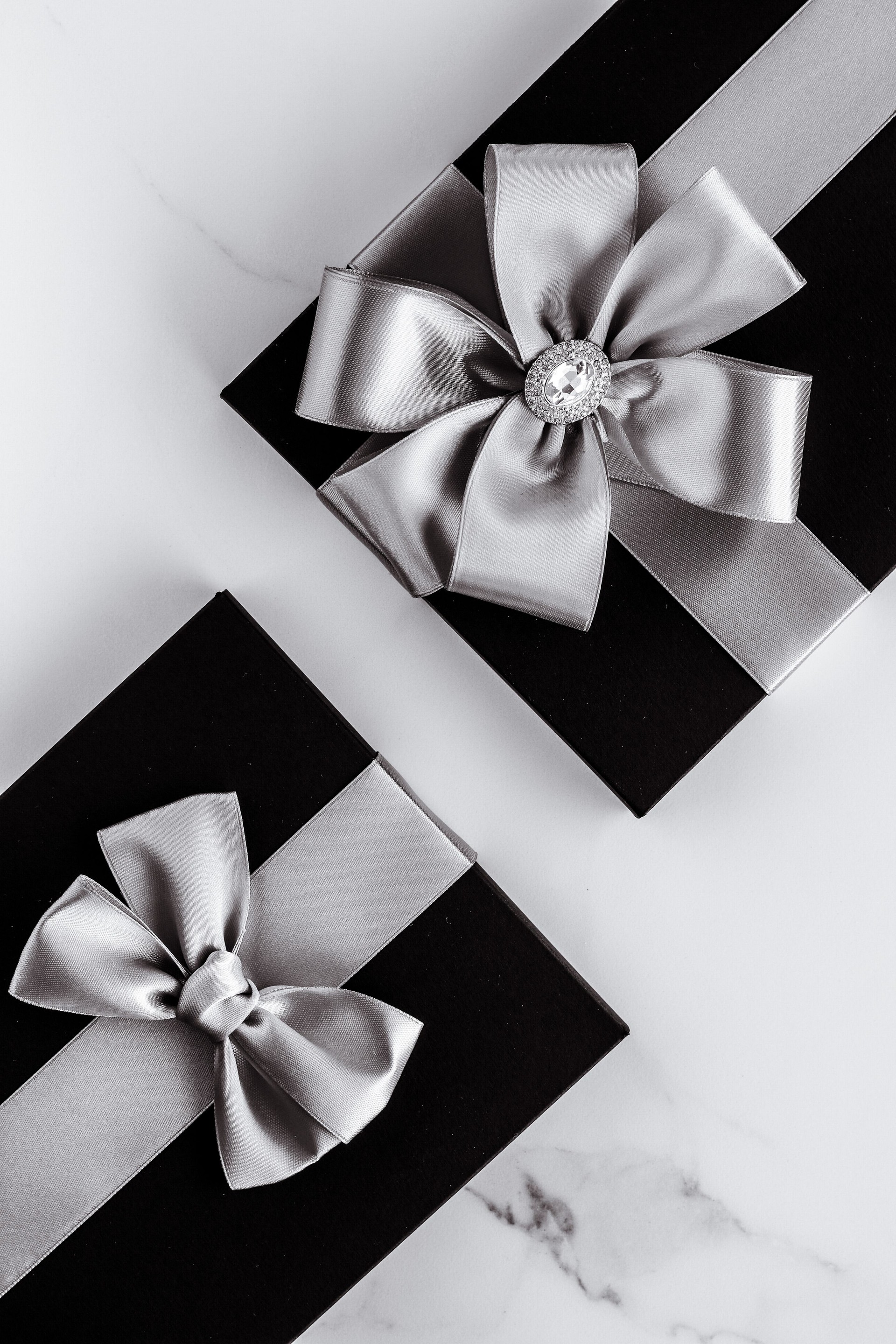 Luxury holiday gifts with silver silk ribbon and bow on marble background